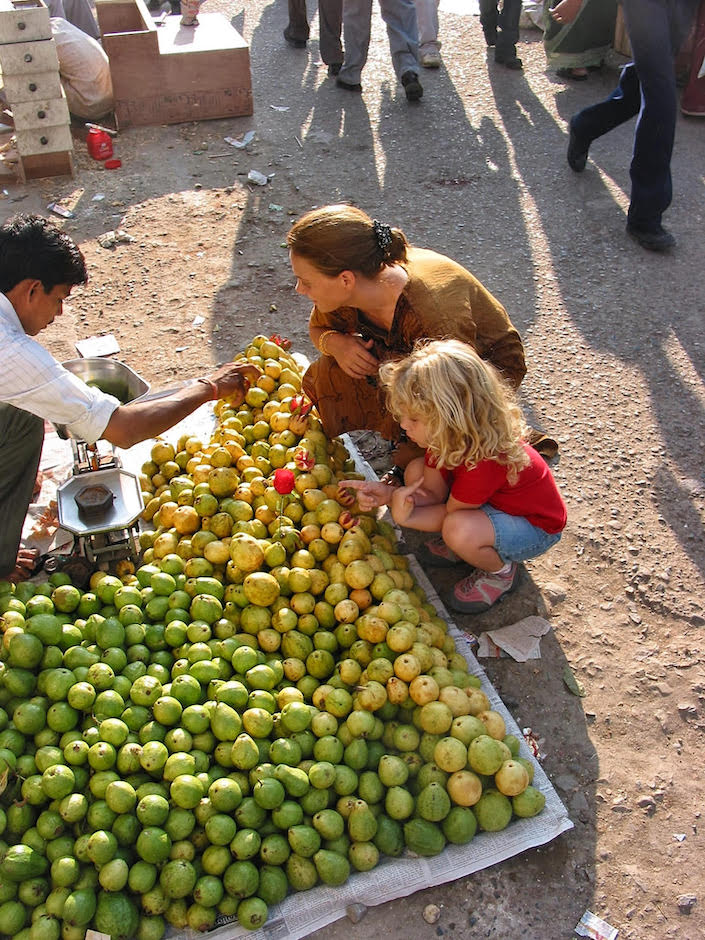 Woman and child kneeling at fruit stand